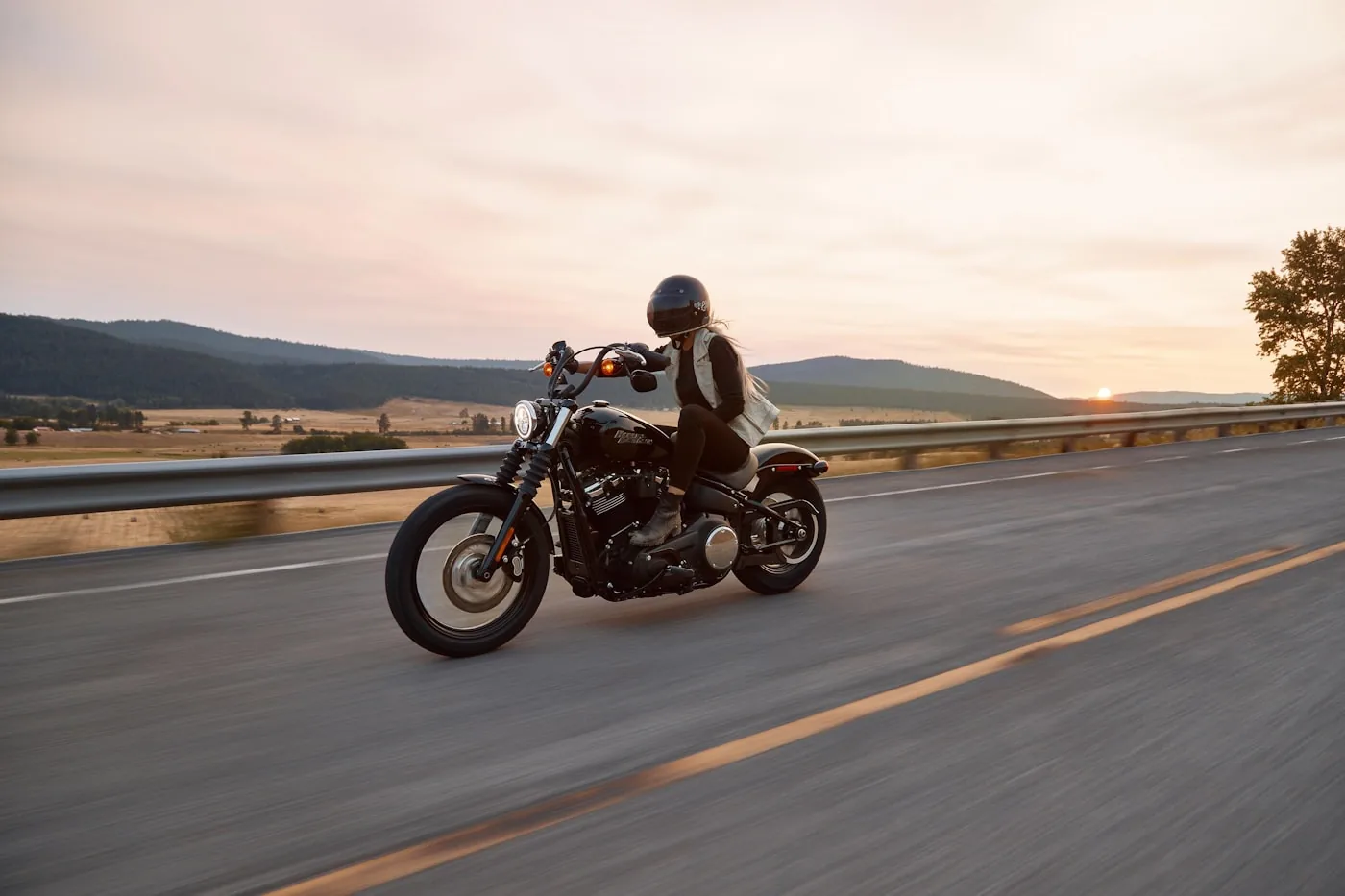 Rider on a motorcycle on an open road at sunset